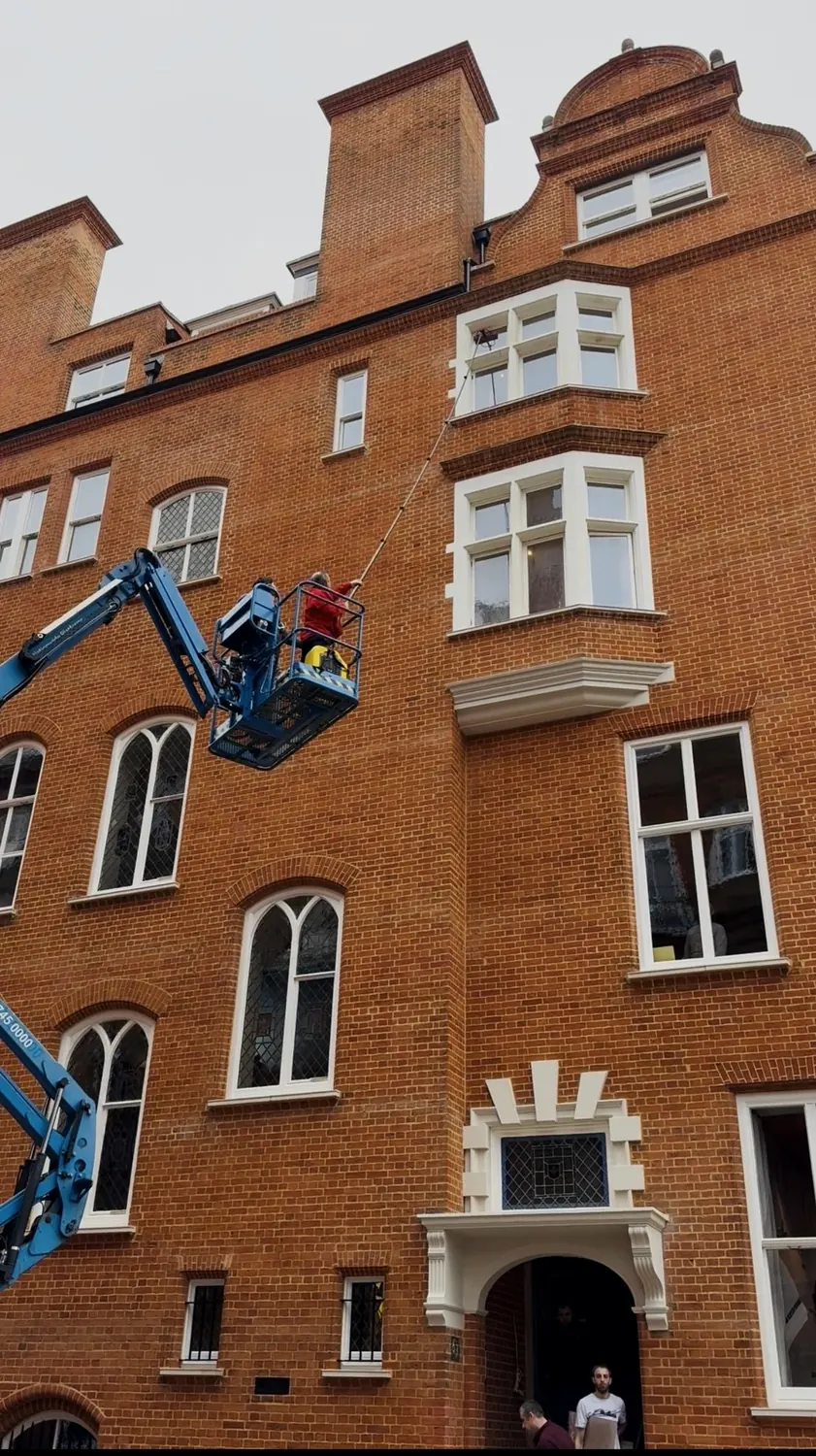 High-level window cleaning on a red-brick London townhouse